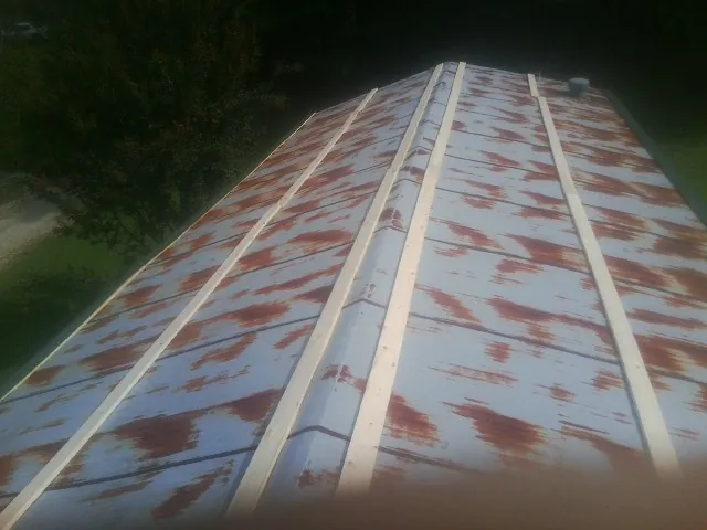 Rusted metal roof panels with new wood purlins before replacement — Storm Damage Roof Repair in Drakesville by Roofing Brothers