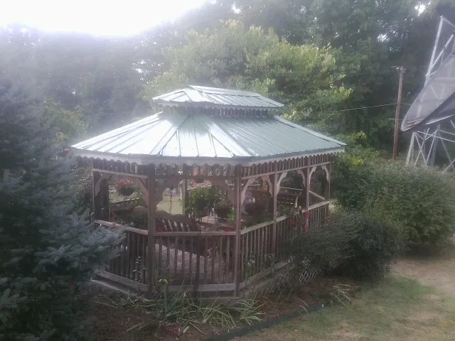 Green metal roof on a backyard gazebo surrounded by garden beds in Drakesville