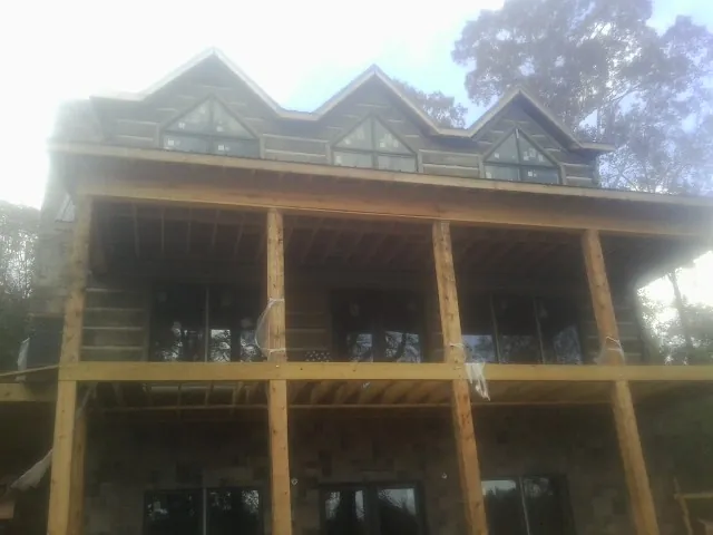 Dormers and porch framing on a large log home under construction — Roof Coating work by our crew in Drakesville