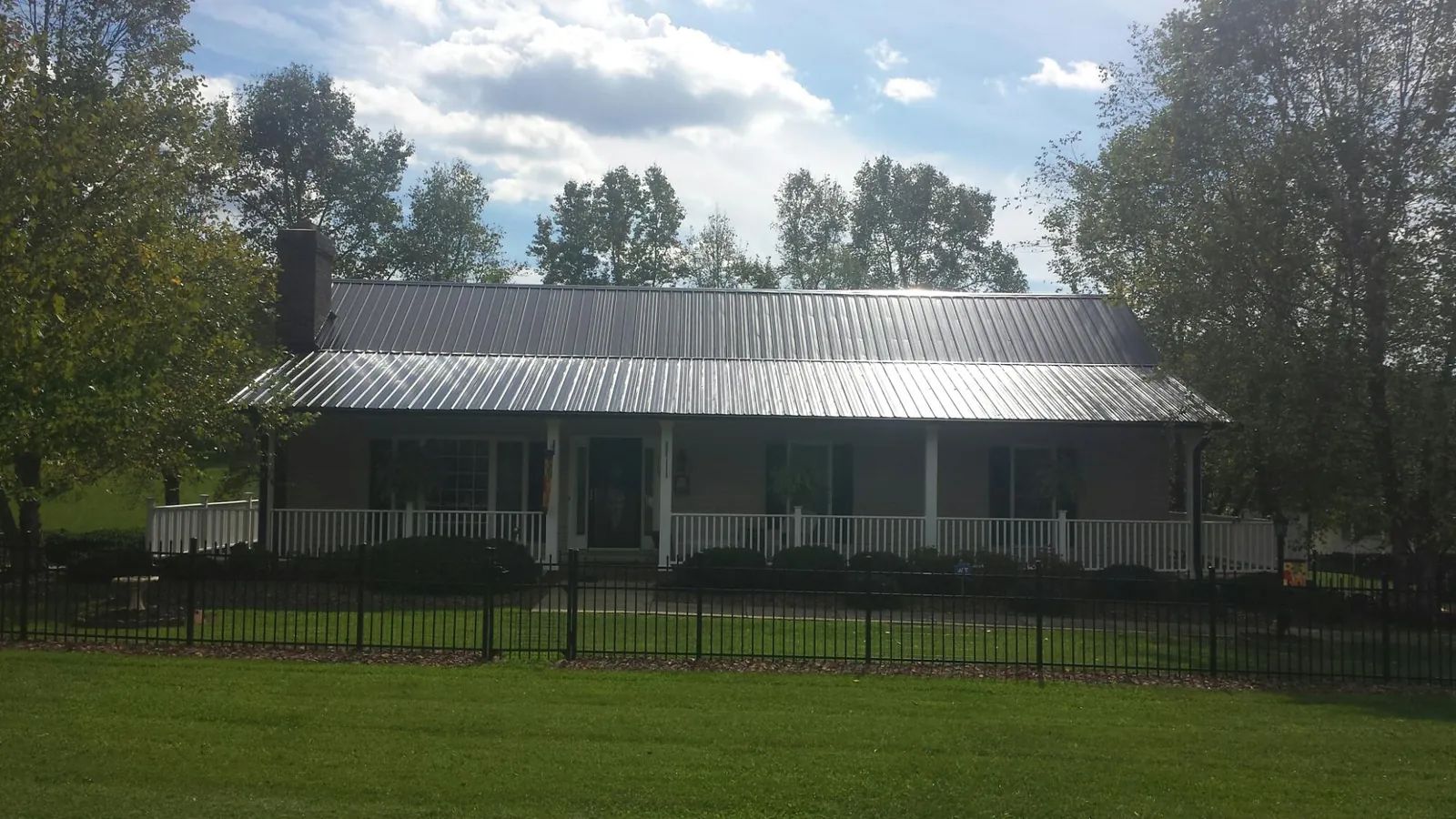 Gray metal roof on a brick ranch with a full width front porch — Gutter Guard Installation work by our crew in Drakesville