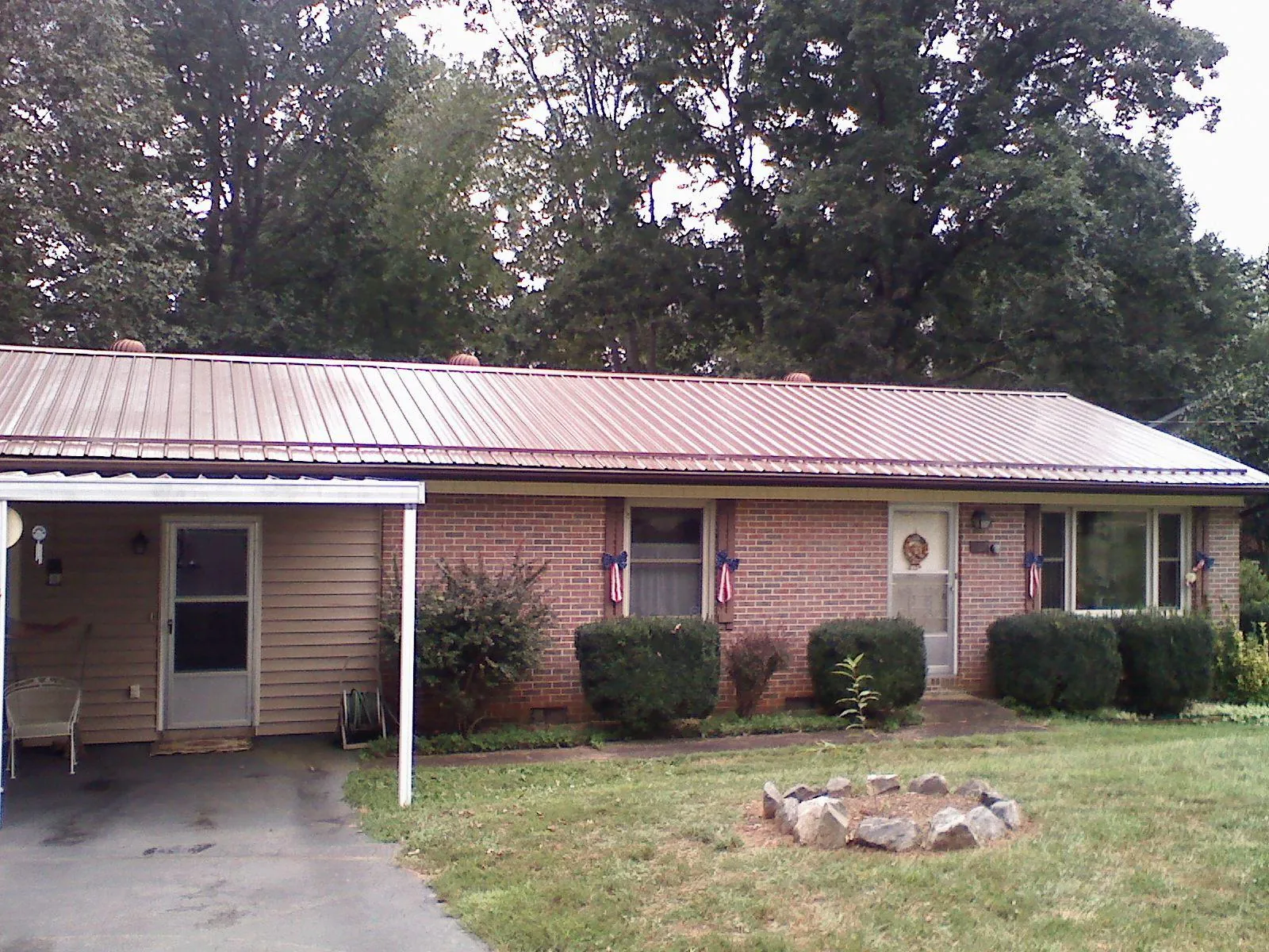 Bronze metal roof and carport on a brick ranch home — Roof Repair work by our crew in Drakesville