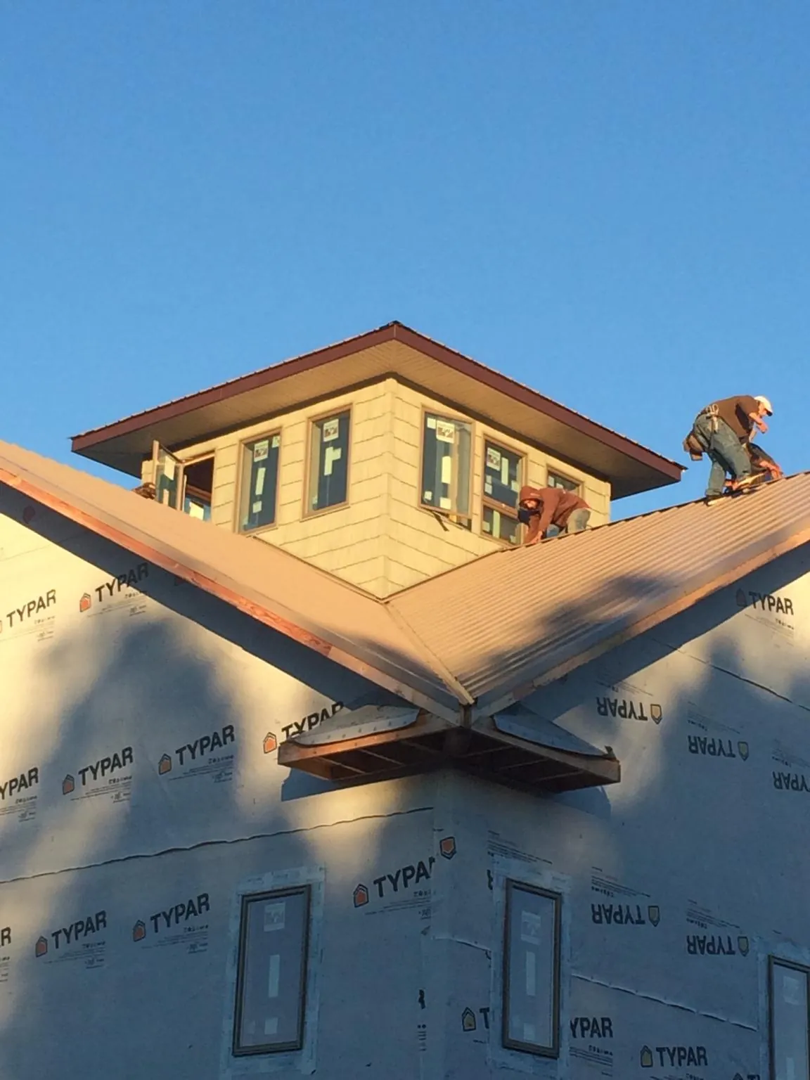 Roofers working around a rooftop cupola on a new metal roof at sunset — Roof Waterproofing in Drakesville by Roofing Brothers